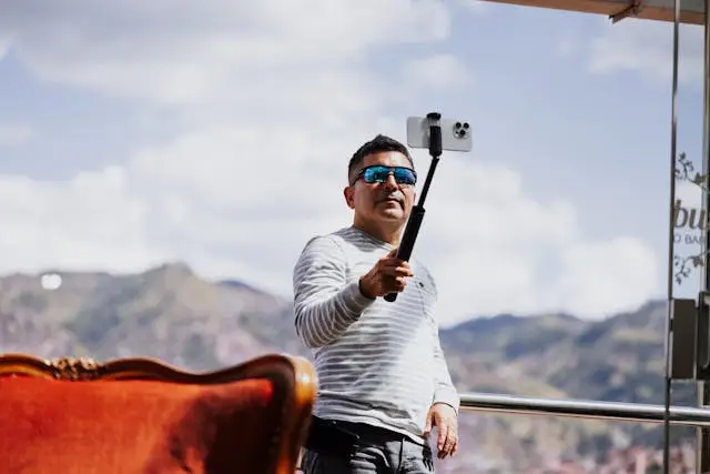 Mies hymyilee ottaessaan selfietä selfiekepillä ja vangitsee ilon hetken ulkona.